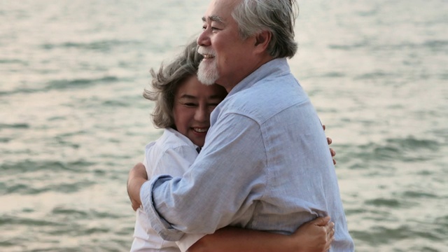 一对老年夫妇在海滩上拥抱。一对老年夫妇在阳光明媚的日子里在海边放松。高级假期,假期视频素材
