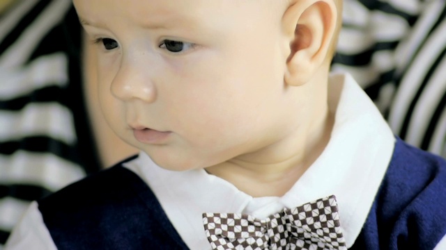 一个6个月大的男孩在他妈妈家附近穿着西装的特写。缓慢的运动。视频下载