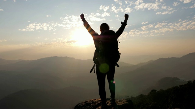 女子徒步到山顶，双手举在头上庆祝成功，慢动作视频素材