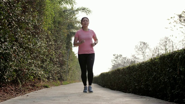 慢镜头:女人在公园里跑步做心脏运动视频素材