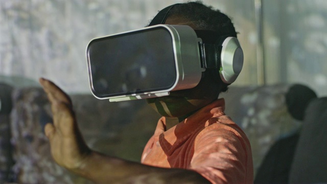 CU SLO MO，一个戴着虚拟现实头盔的非裔美国男孩把手伸到面前。视频素材