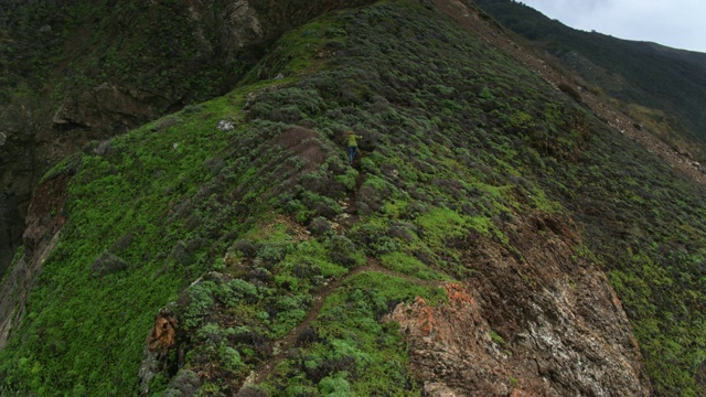 无人机拍摄的女人爬上大苏尔的山脊视频素材