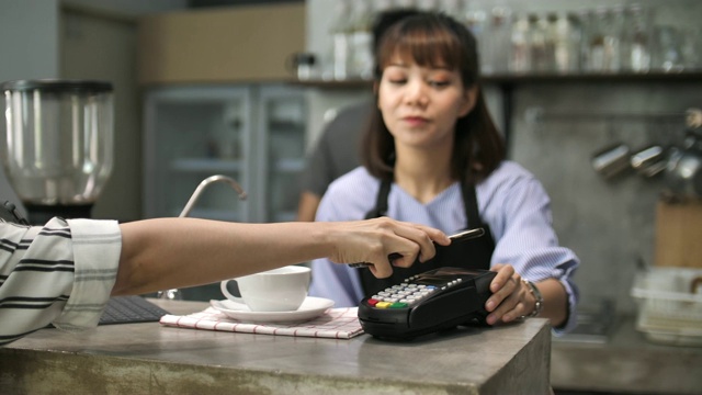 女性顾客尝试用智能手机刷卡支付，非接触式支付视频素材