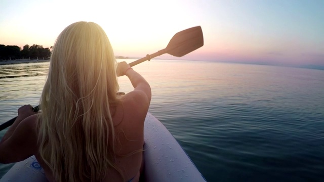 日落时分，一名年轻女子在爱琴海上划皮艇视频素材