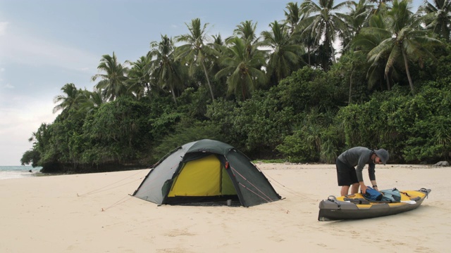 一名男子带着皮划艇在太平洋岛屿上露营视频素材