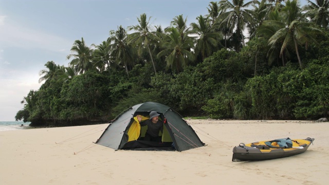 在太平洋岛屿上，一名男子向帐篷外望去视频素材