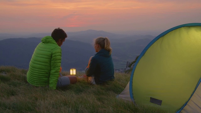 慢镜头:一对无忧无虑的夫妇在阿尔卑斯山露营，观察夜晚的风景视频素材