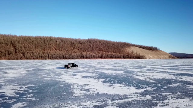 无人机鸟瞰图的汽车在冬季景观和高速驾驶在冰冻的湖面上。视频素材