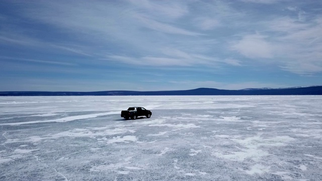 无人机鸟瞰图的汽车在冬季景观和高速驾驶在冰冻的湖面上。视频素材