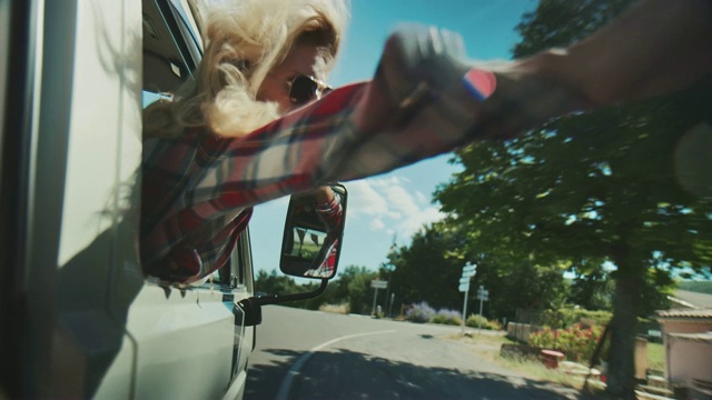 一个女人在阳光明媚的日子里透过车窗挥手视频下载