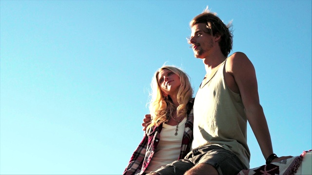 一对夫妇在阳光明媚的日子里坐在车顶上视频素材