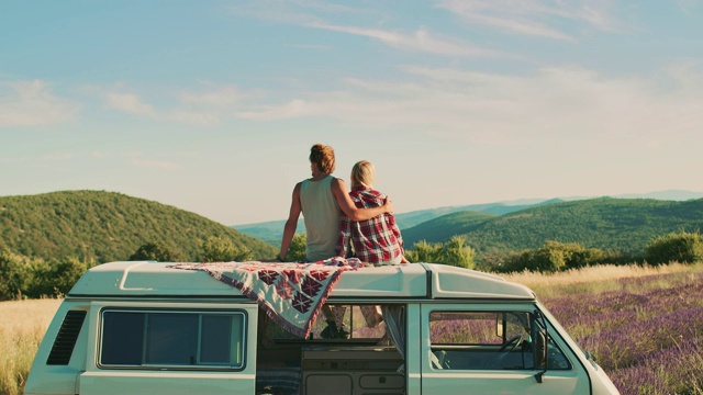 一对夫妇坐在车顶上欣赏风景视频素材