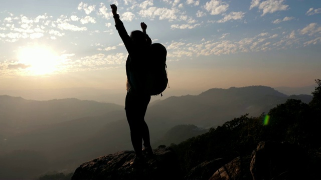 女子徒步到山顶，双手举在头上庆祝成功，慢动作视频素材