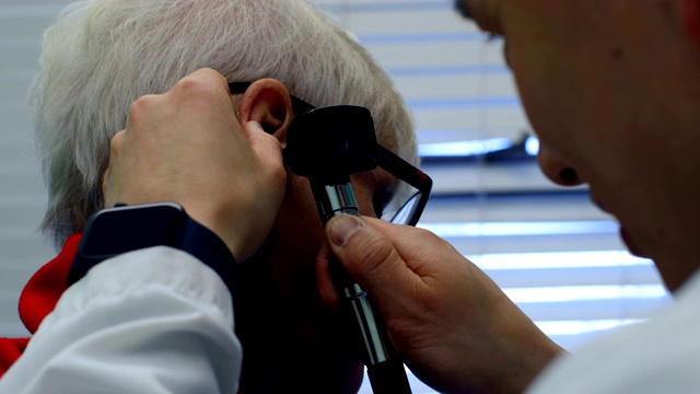 年轻的亚洲男医生在4k诊所用耳镜检查一位老年病人视频下载