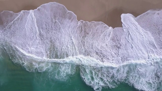 无人机在海滩上海浪破碎的海滩海岸线海浪的视图。——延时视频素材