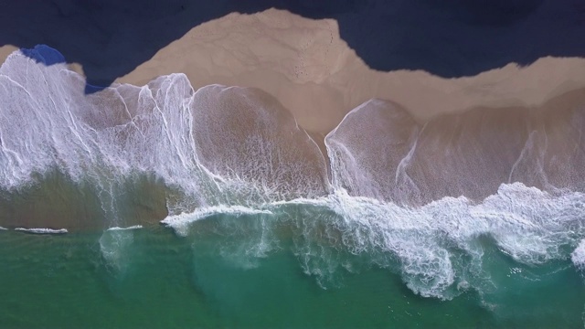 无人机在海滩上海浪破碎的海滩海岸线海浪的视图。——延时视频素材