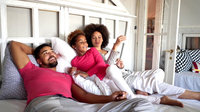 可爱的混血家庭躺在床上享受这一天视频素材