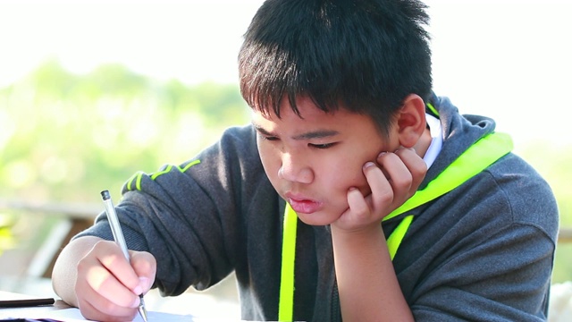 亚洲男孩做写作学习作业考试在书桌上在家户外自学教室。教育学习理念。4K视频下载