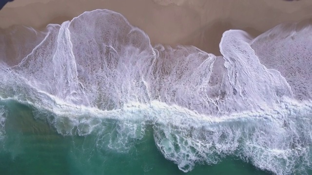 无人机在海滩上海浪破碎的海滩海岸线海浪的视图。视频素材