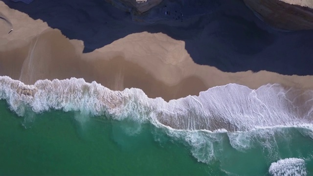 无人机在海滩上海浪破碎的海滩海岸线海浪的视图。视频素材