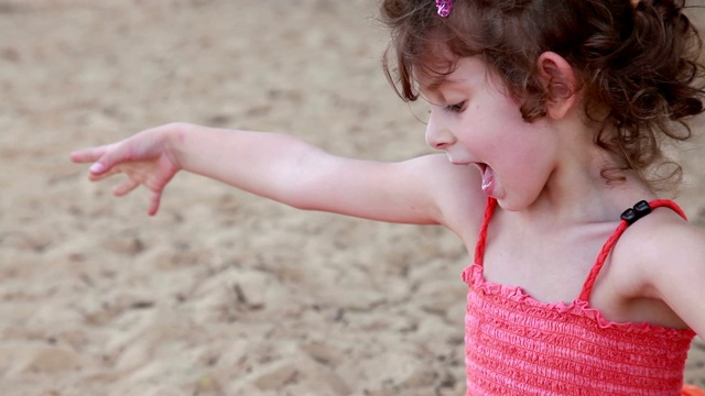 一个快乐的小女孩在沙滩上玩沙子的特写视频素材