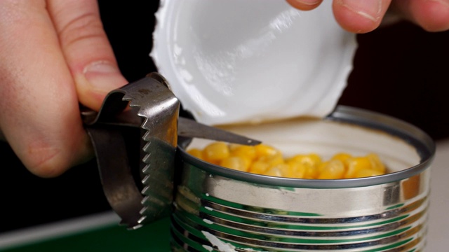 特写的手使用手动开罐器打开一个罐头的食物和移开盖子的顶部。视频下载