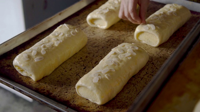 面点师傅手将杏仁放在生面团上，准备将面包放入烤箱。视频素材