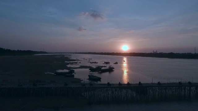 空中摇摄的汽车和摩托车在日落时穿过一条河上的竹桥视频下载
