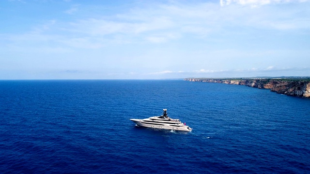 鸟瞰地中海上的一艘游艇，在蓝色的海水中反射着太阳。游艇在悬崖附近航行。11、地平线上只有海，蓝天下有海。视频下载