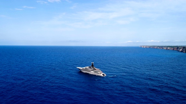 鸟瞰图与一艘游艇在地中海，与蓝色海水的太阳反射。游艇在悬崖附近航行。11、地平线上只有海，蓝天下有海。视频下载