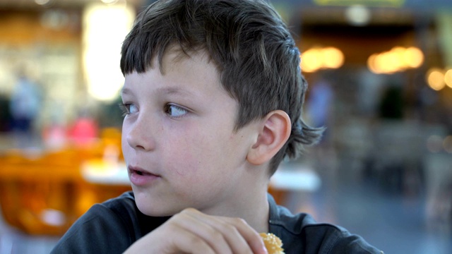 男孩吃了一个黑色的汉堡近距离视频素材