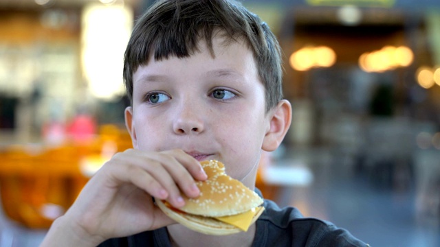 男孩吃了一个黑色的汉堡近距离视频素材
