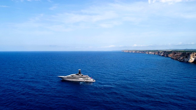 美丽的航拍一艘游艇在地中海，与蓝色海水的太阳反射。游艇在悬崖附近航行。11、地平线上只有海，蓝天下有海。视频下载