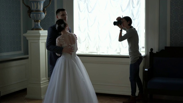 后台婚纱摄影-专业摄影师在别致的房间里为新婚夫妇拍照视频素材