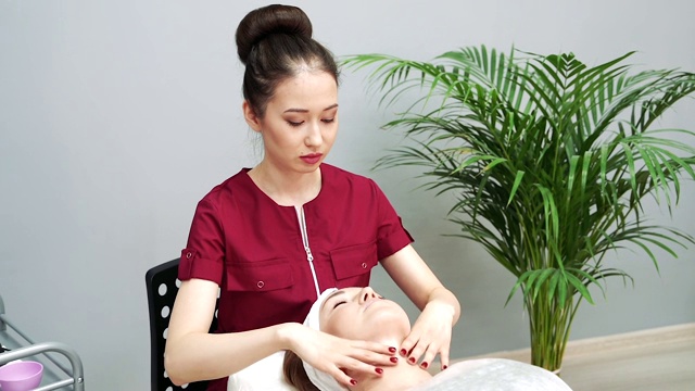 亚洲女性美容师使放松面部按摩年轻女性视频下载