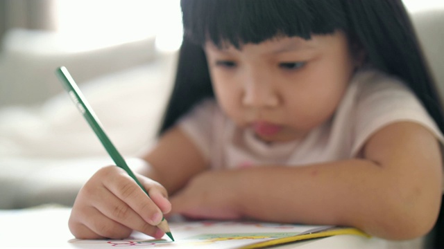 小女孩在学校的画册上写字，慢镜头视频素材