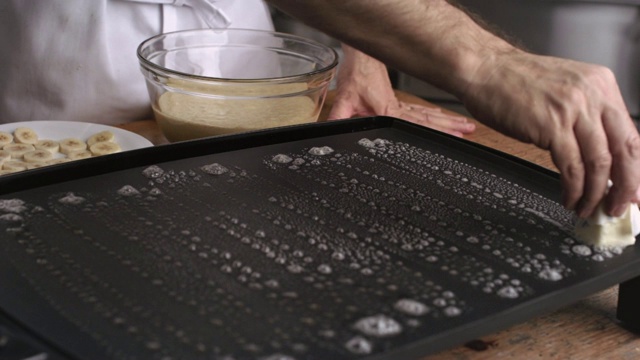 厨师用手拿黄油棒在热平底锅上抹黄油薄饼视频素材