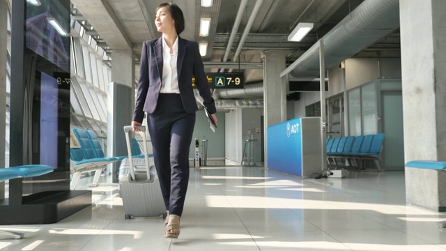 亚洲女商人在机场拉手提箱，商务旅行视频素材