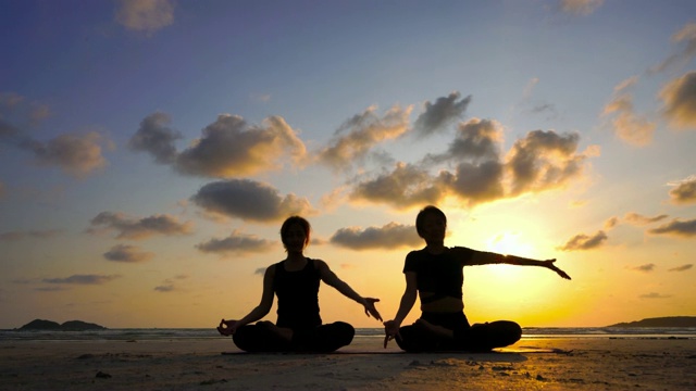 日落时分，在海滩上练习瑜伽的女人的剪影视频下载