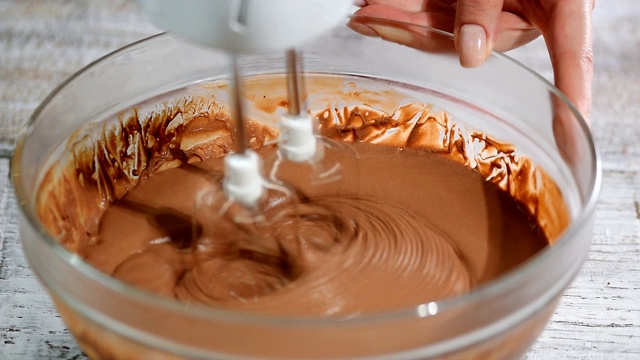 用电动搅拌机搅拌巧克力。烹饪混合和准备巧克力奶油。视频素材
