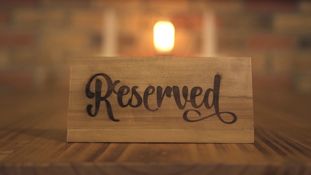 烛光晚餐晚餐餐厅的预定桌位标志。在豪华餐厅或咖啡厅预订木牌桌，浪漫约会和烛光晚餐视频下载