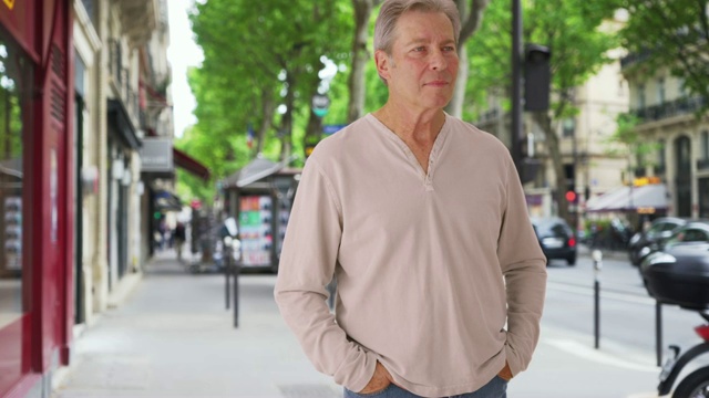 在巴黎的人行道上，自信成熟的白人男子环顾四周，然后对着镜头微笑视频下载