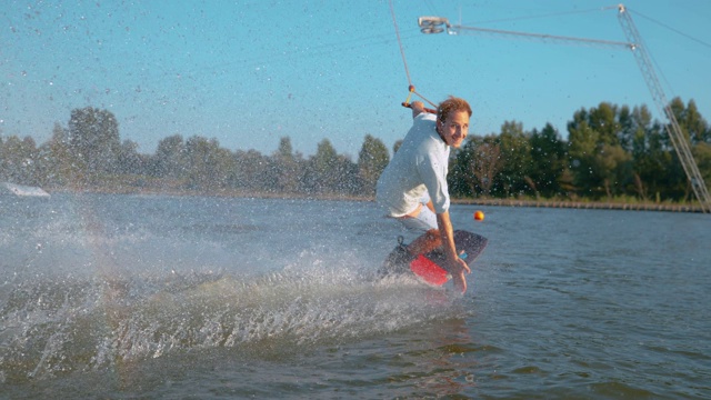 特写:微笑的滑水者喷洒着湖水，他的速度超过了镜头视频素材
