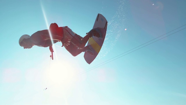 镜头光晕:快乐的wakesurfer在飞过镜头时做了一个很酷的翻转戏法视频下载