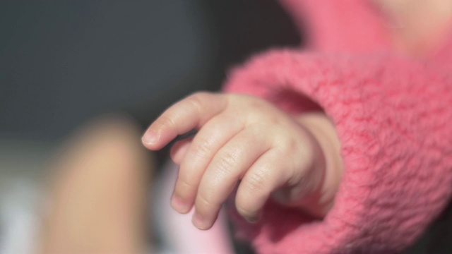 穿着粉红色夹克的小婴儿的手被遮住了视频下载