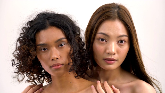 头部镜头:美丽的亚洲肤色和白人妇女在白色的背景。人以美容、保健、情感为理念。视频素材