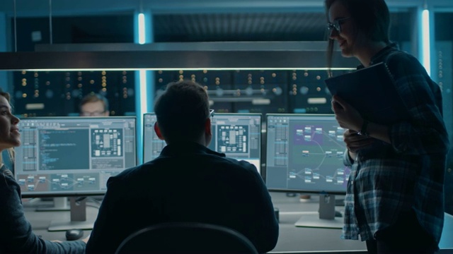 男、女IT工程师程序员在配备服务器机架的系统控制室台式机上编码。显示软件开发代码编写过程视频素材