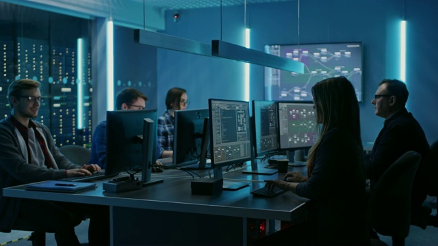 在数据中心系统控制室的台式电脑上工作的年轻IT程序员团队。显示显示概念:软件开发/代码编写/数据库架构。技术部门视频素材
