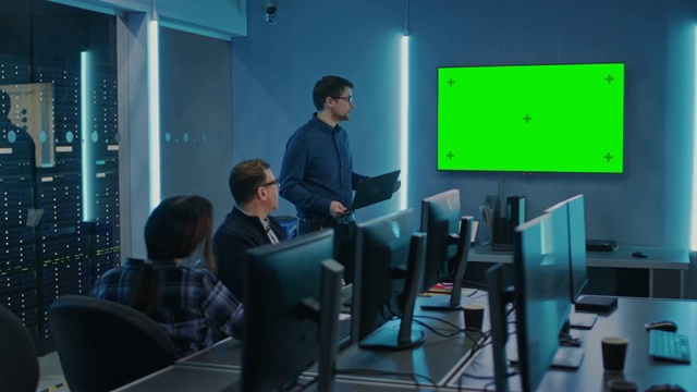 专业IT开发团队开会，演讲者谈论新概念，墙上电视有绿色模拟屏幕。概念:软件开发，深度学习，人工智能，数据挖掘视频素材