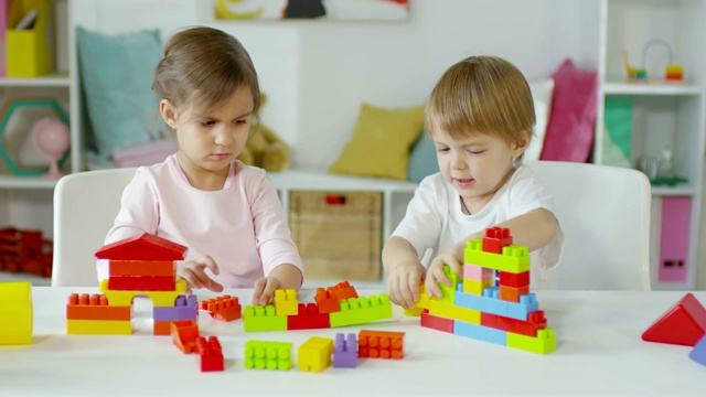 两个孩子坐在桌子旁玩建筑玩具视频下载